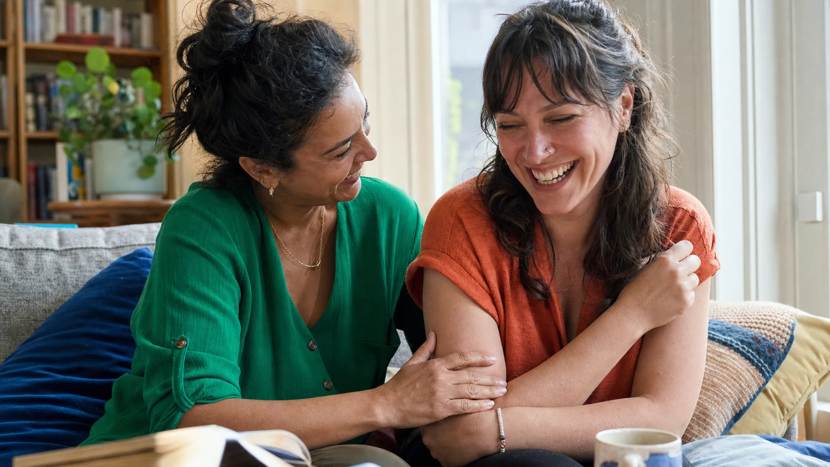 Two close friends sharing warmth and relieved laughter in a sunlit home
